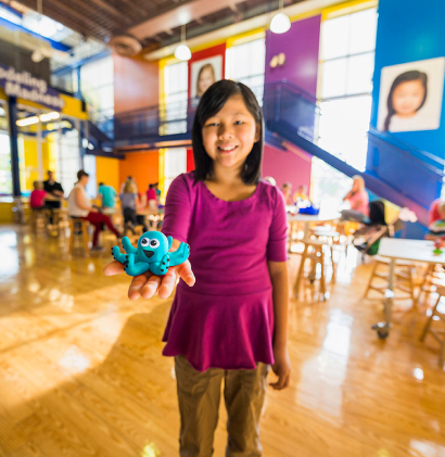 Girl displaying her Crayola sculpture of a blue octopus