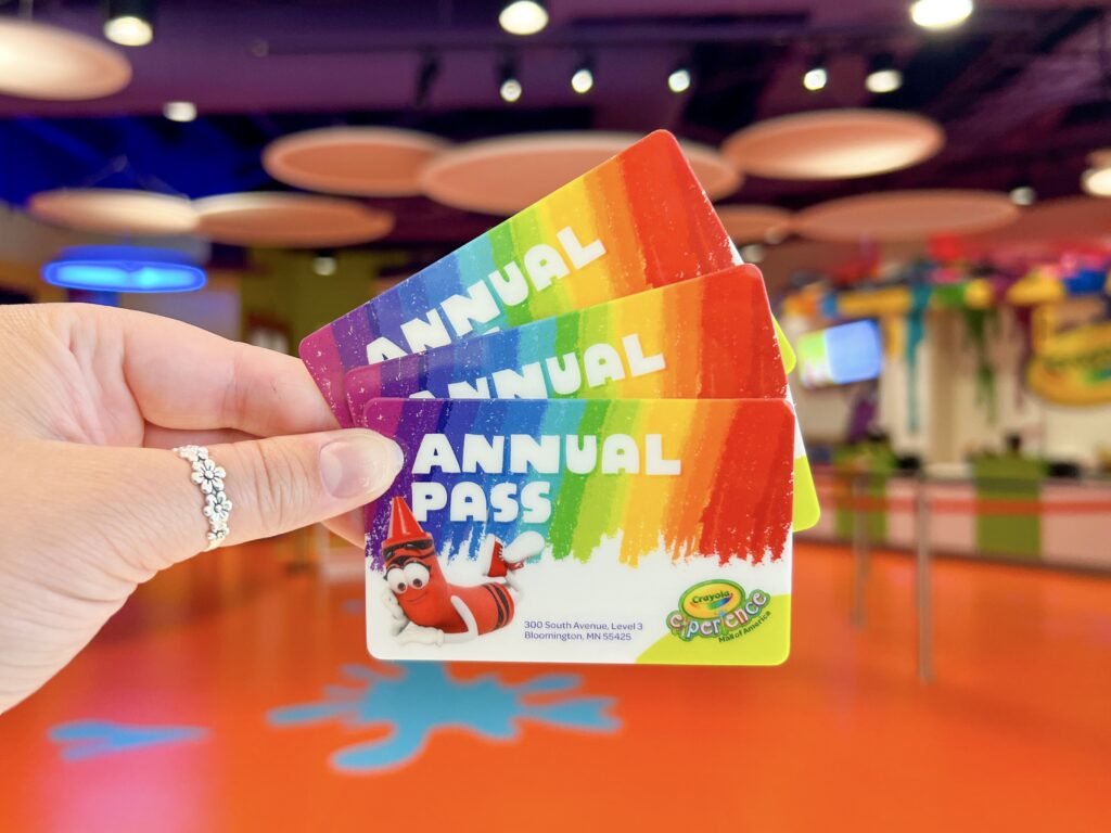three raibow annual pass cards are held in front of Crayola Experience